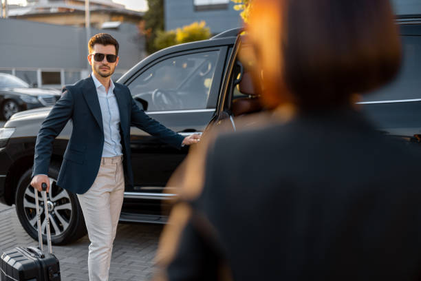 Chauffeur assisting a traveller with luggage beside a black SUV at dusk