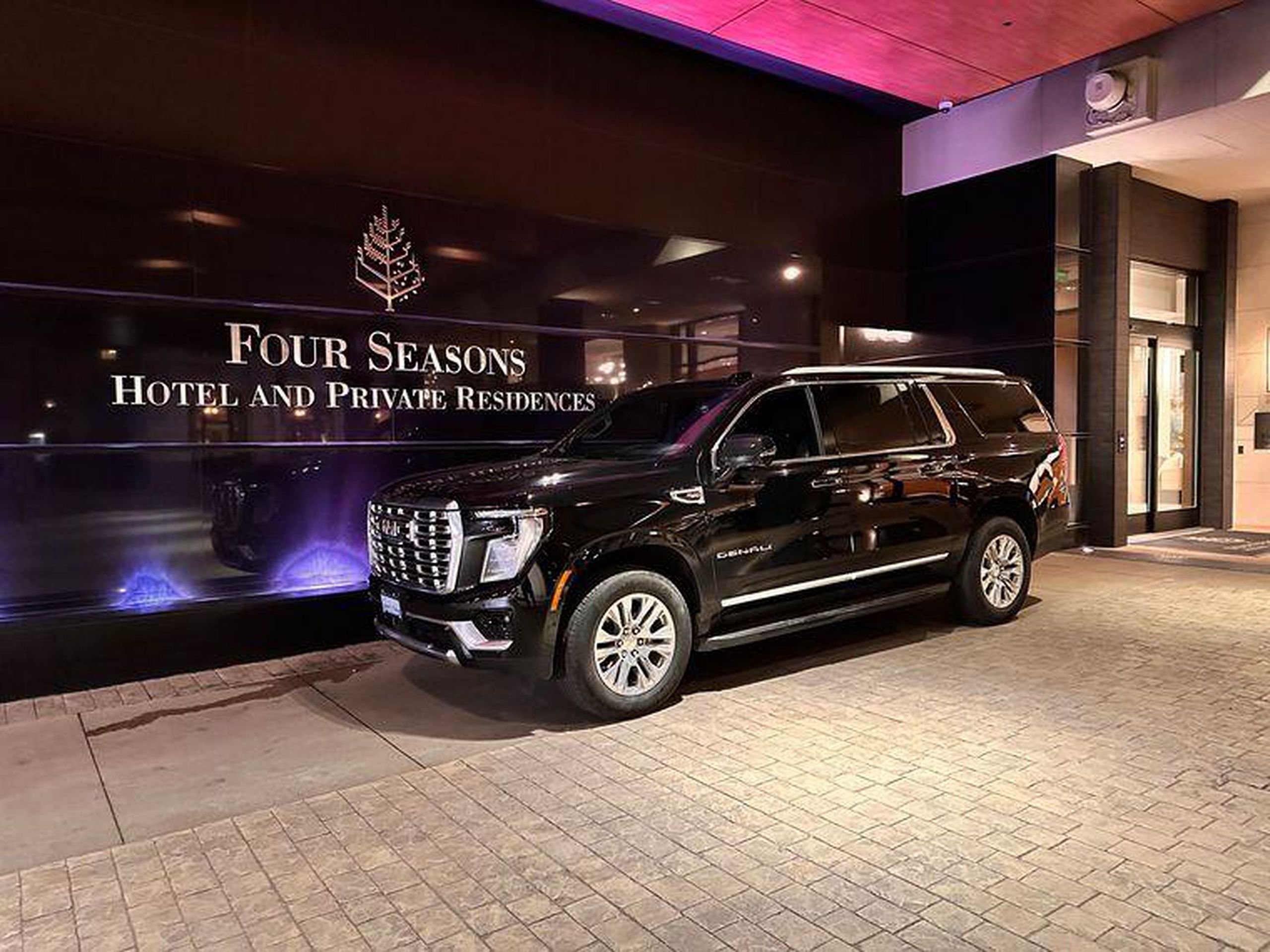 Black GMC Yukon Denali chauffeur SUV waiting at the Four Seasons Hotel entrance in Toronto