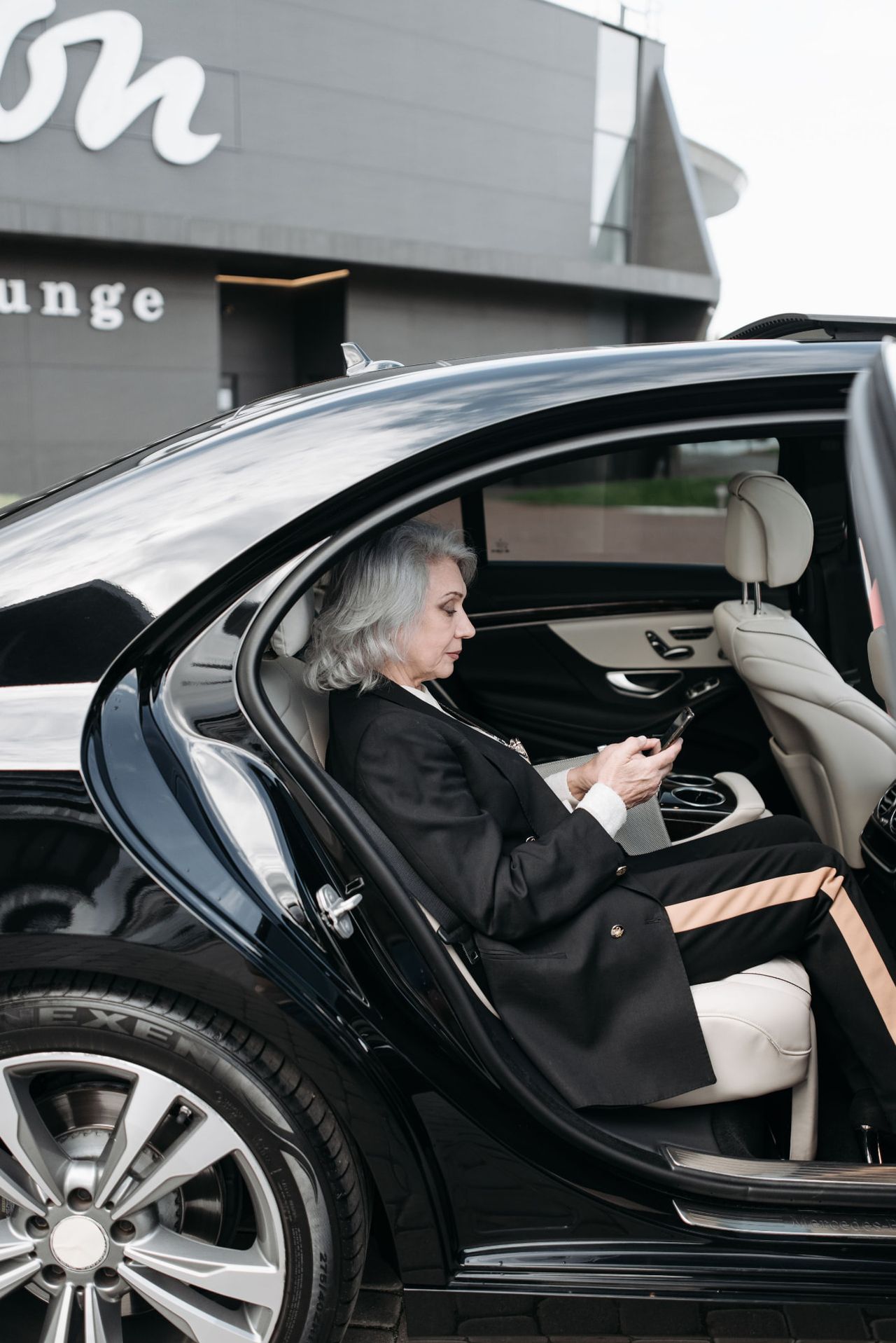 Executive passenger seated in the cream leather back seat of a black luxury vehicle